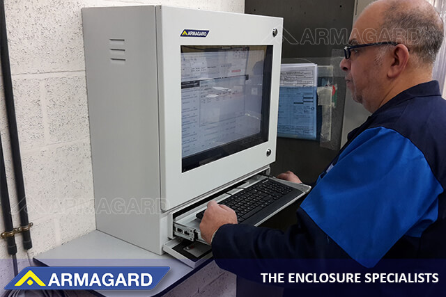 A worker using an NEMA 4 shop-floor computer workstation